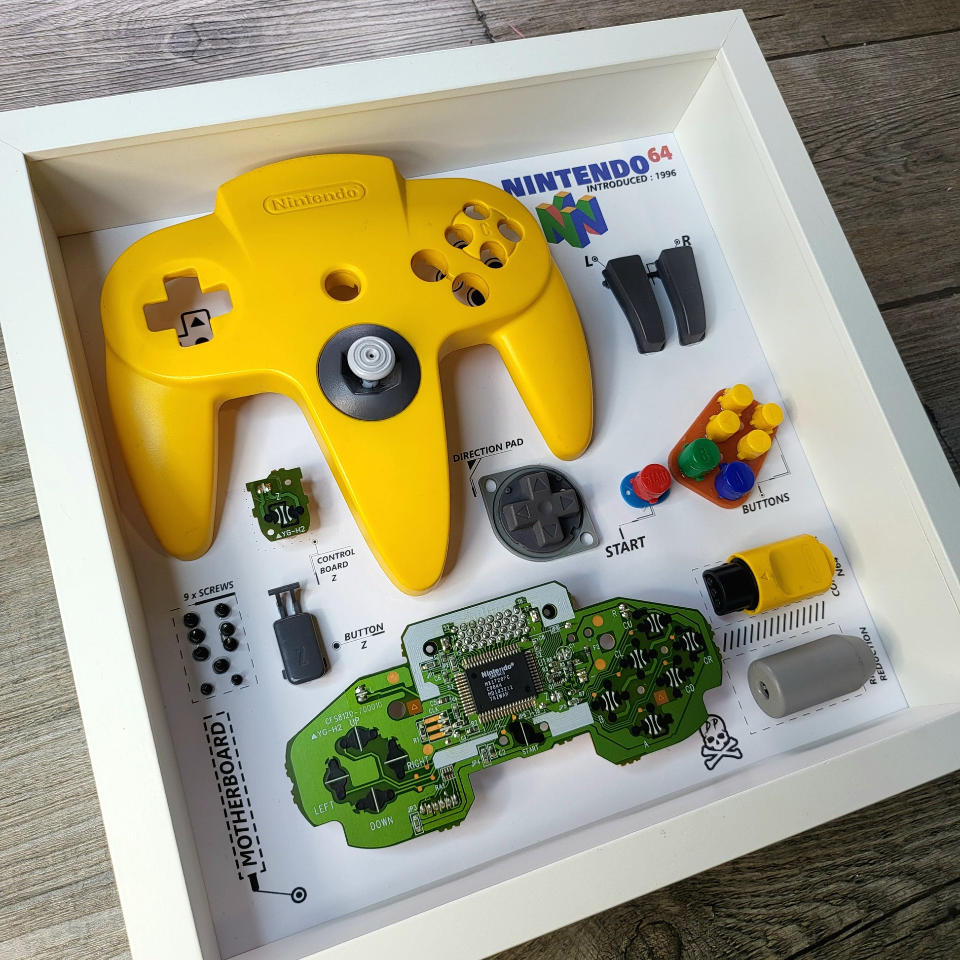Shadow Box 10x10 with wood frame and polycarbonate glass for wall and Tabletop containing a disassembled controller for Playstation and Nintendo